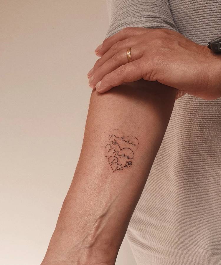 A imagem exibe uma tatuagem no antebraço de uma pessoa, representando um coração formado por uma linha pontilhada. Dentro dele, as palavras "gratidão", "Mãe" e "Pai" estão escritas em caligrafia delicada. Um anel dourado é visível na mão da pessoa, que veste uma camisa listrada.





A imagem exibe uma tatuagem no antebraço de uma pessoa, representando um coração formado por uma linha pontilhada. Dentro dele, as palavras "gratidão", "Mãe" e "Pai" estão escritas em caligrafia delicada. Um anel dourado é visível na mão da pessoa, que veste uma camisa listrada.









