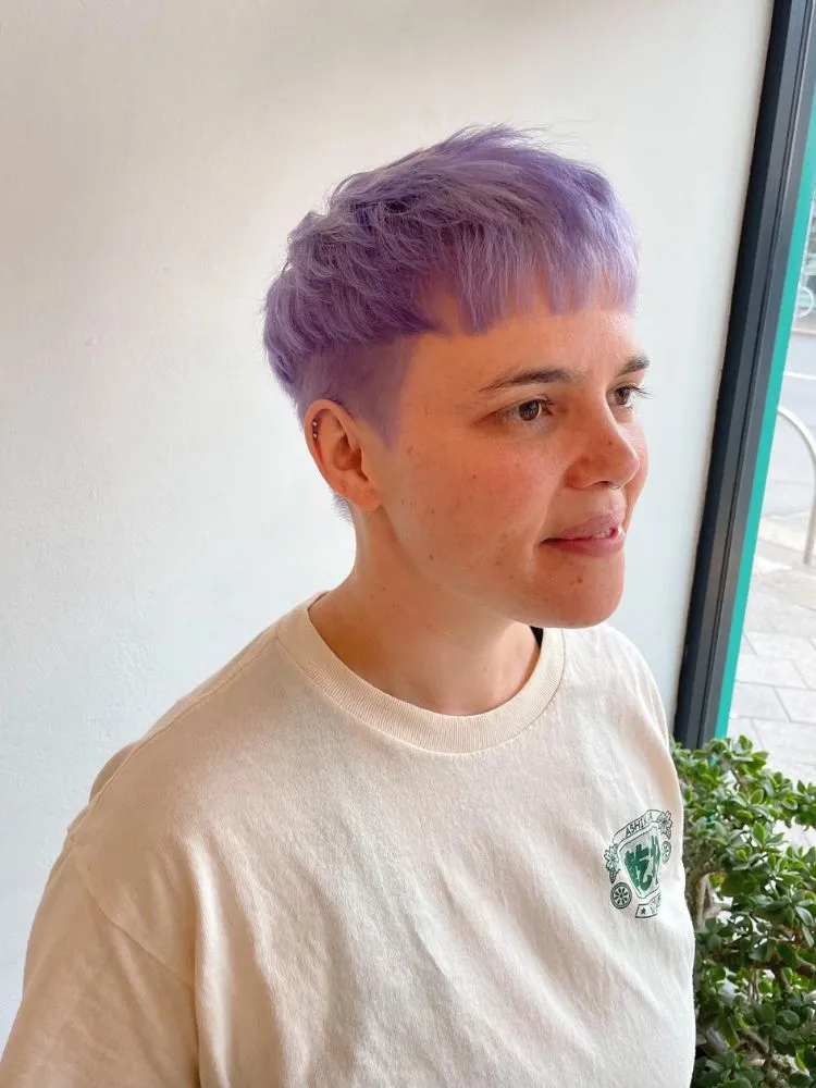Mulher com cabelo lilás em bowl cut repicado