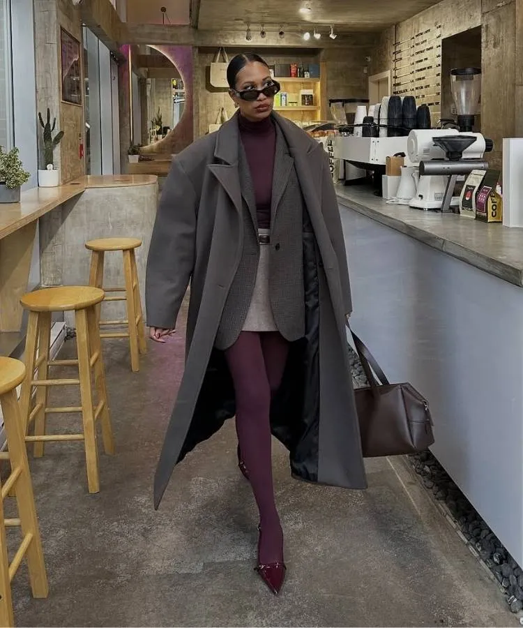 Mulher usando look com meia-calça vinho, slingback, saia bege, blusa vinho e sobretudo cinza