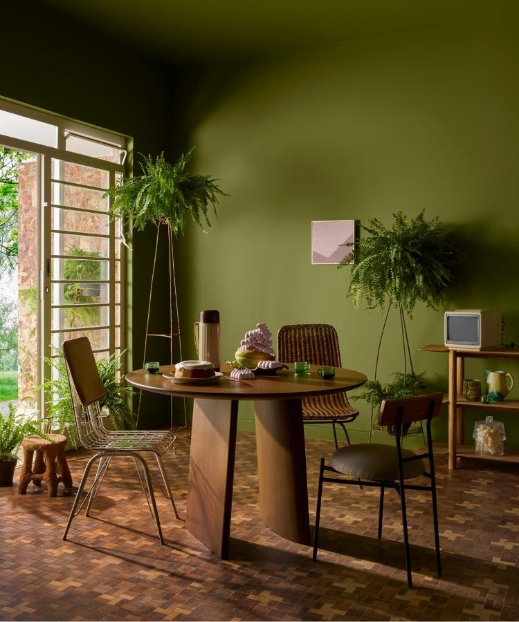 Sala de jantar com parede pintada com a tinta Cipó da Amazônia, uma das cores do ano 2026 da Suvinil