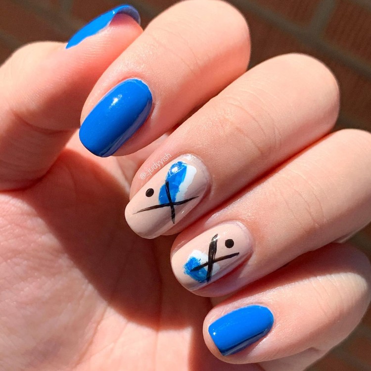 Unhas curtas azuis com médio e anular em nude com desenhos abstratos