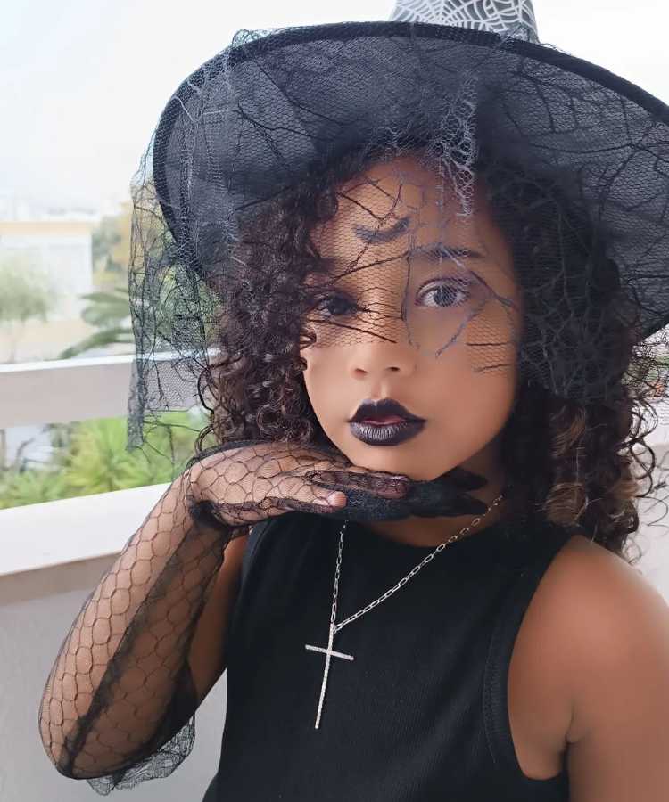 Garota maquaida de bruxa para o Halloween: Cores predominantes: preto. Usa: make com batom e lua no meio da testa