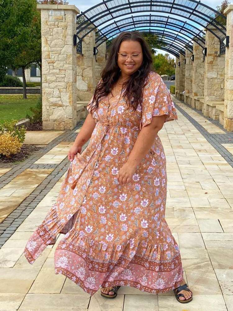 Mulher de pele morena usando vestido fluido marrom com flores