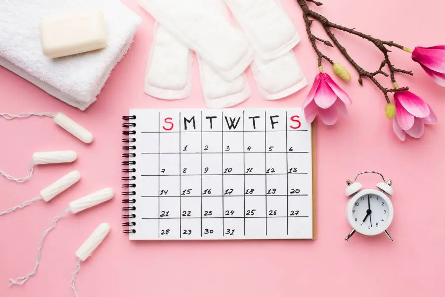 Calendário com absorventes, flores e relógio ao redor.