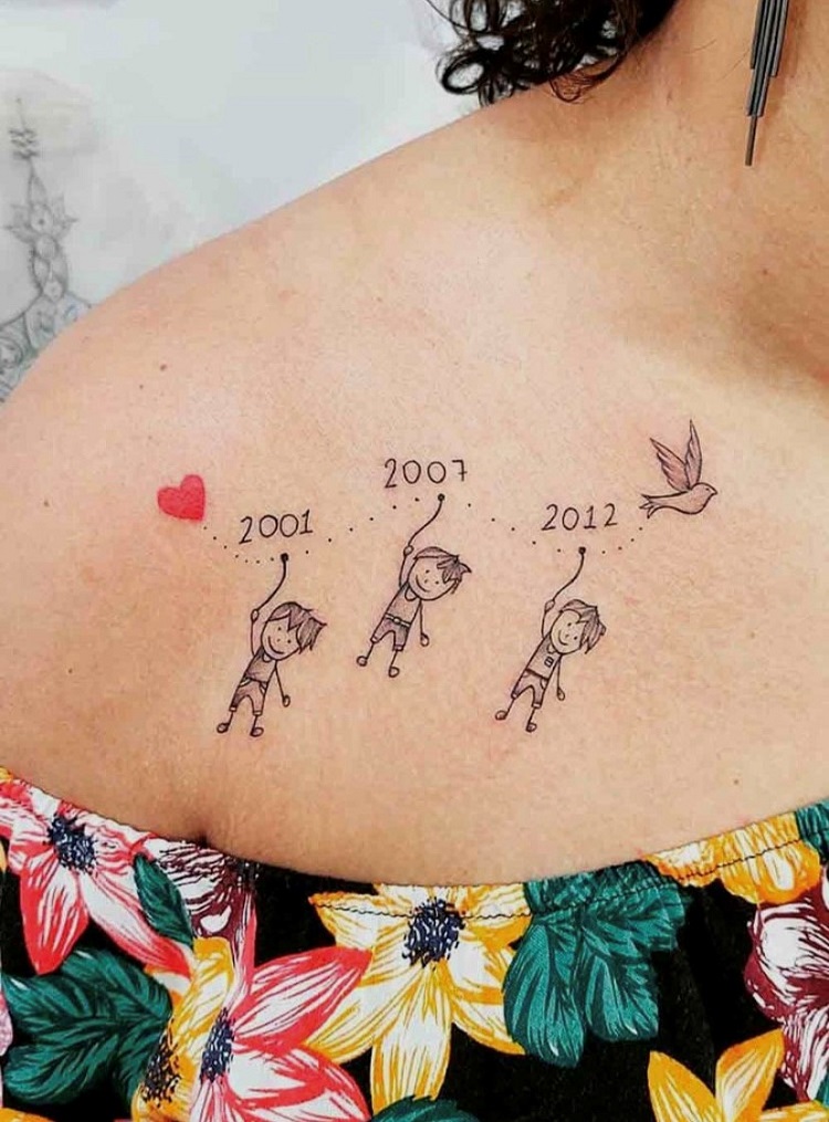 Tatuagem no ombro com varal com coração, pássaro e desenho de 3 meninos com o ano de nascimento