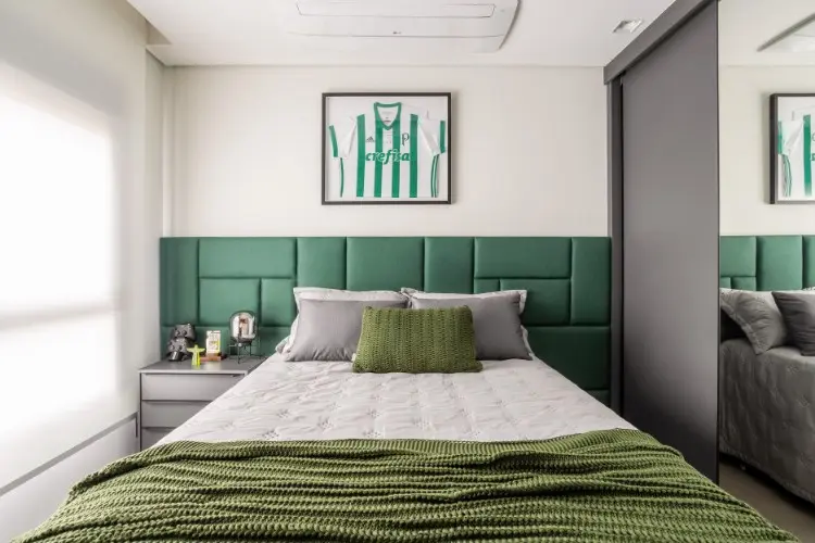 Quarto com cabeceira verde, camisa do Palmeiras enquadrada, cama de casal com lençol branco e manta verde