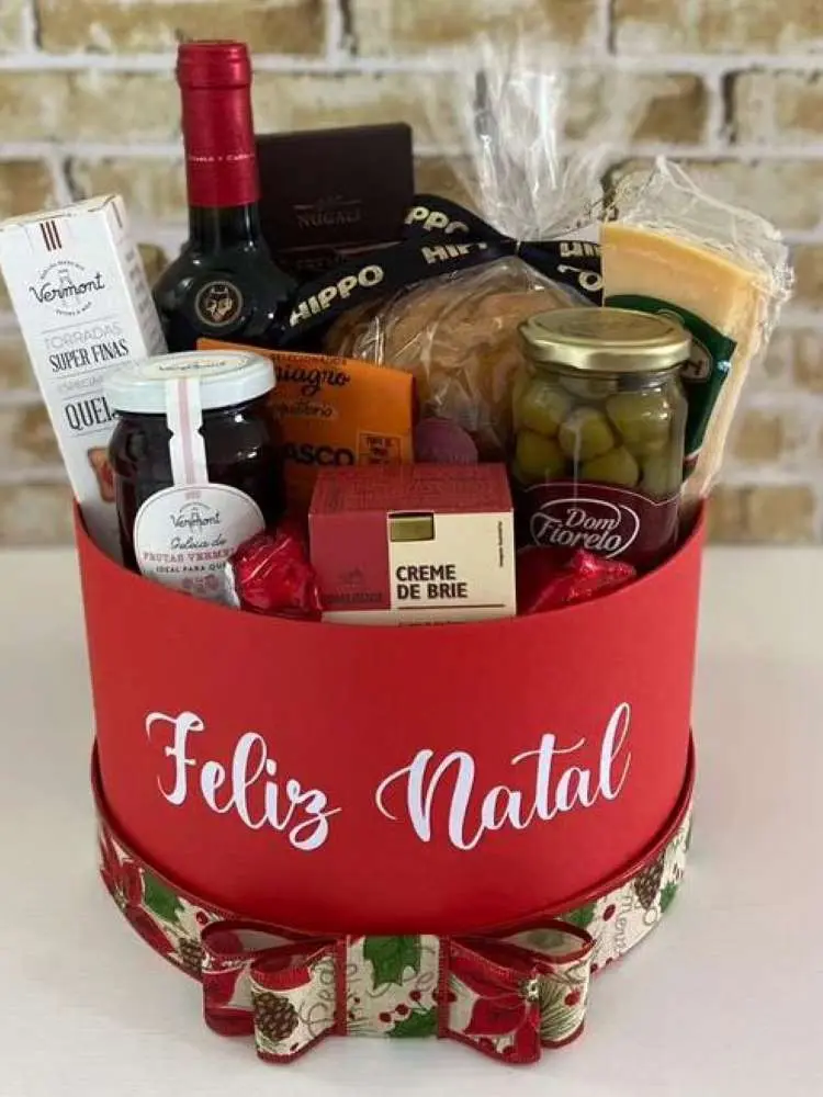 Caixa vermelha escrito Feliz Natal com queijos, vinho e azeitona. 