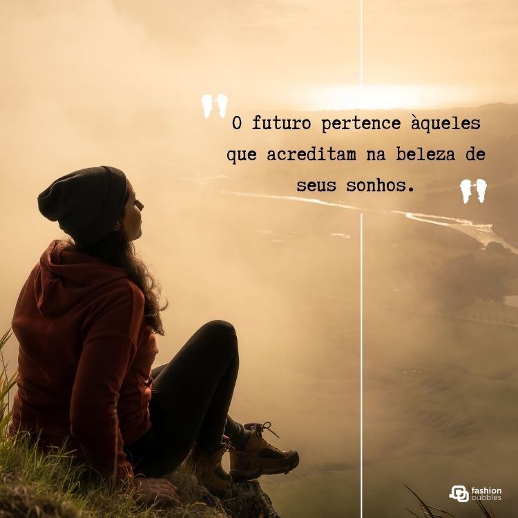Mulher sentada sobre um penhasco, vestindo moletom vermelho e gorro preto, olhando o horizonte nebuloso em tons dourados. Texto à direita: "O futuro pertence àqueles que acreditam na beleza de seus sonhos." Logotipo Fashion Bubbles no canto inferior direito.