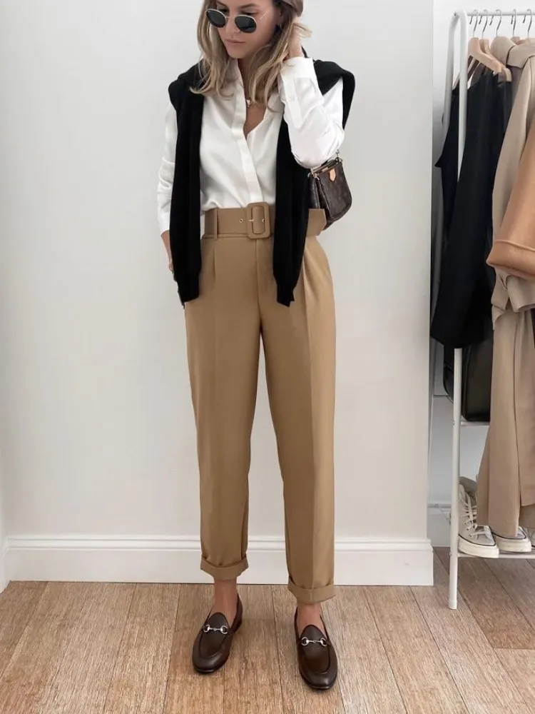 Mulher usando mocassim com calça de alfaiataria bege