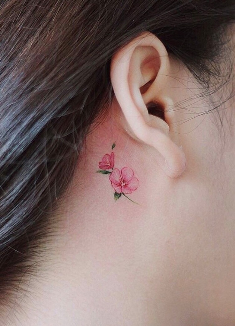 Tatuagem feminina atrás da orelha com flores pequenas coloridas