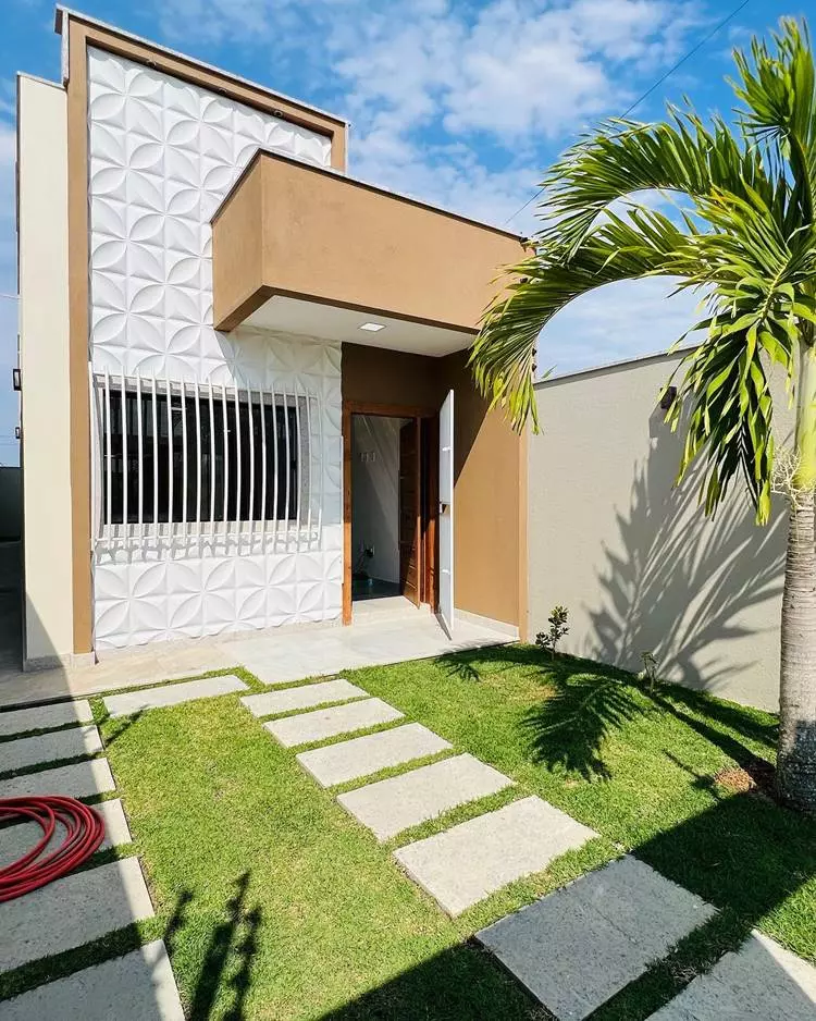 Imagem de fachada de casa simples, decorada com peças em 3D na parede, grade na janela, caminho de pedras retangulares em gramado para carro ficar estacionado
