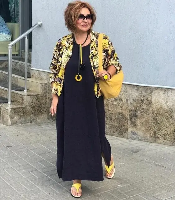Senhora com look estiloso de vestido preto com casaco estampado e acessórios amarelos - Sou plus Size