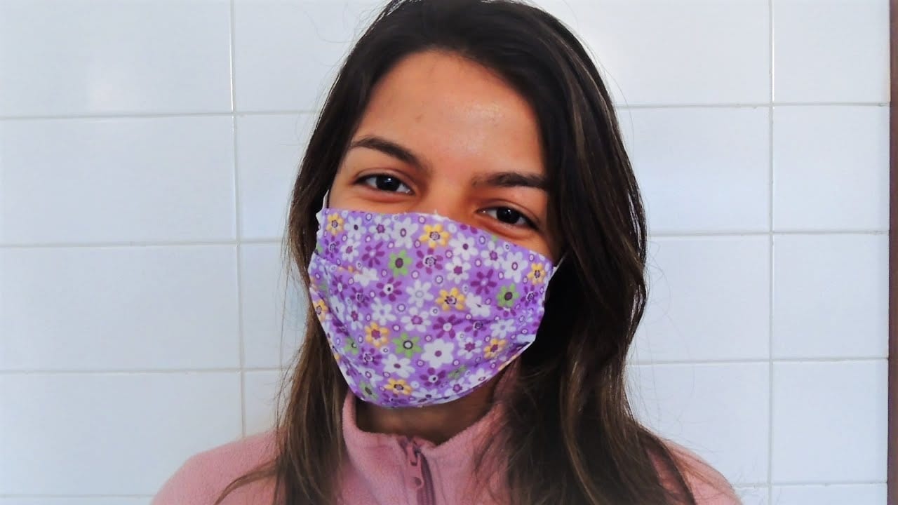 Mulher sorrindo usando máscara com estampa floral alegre