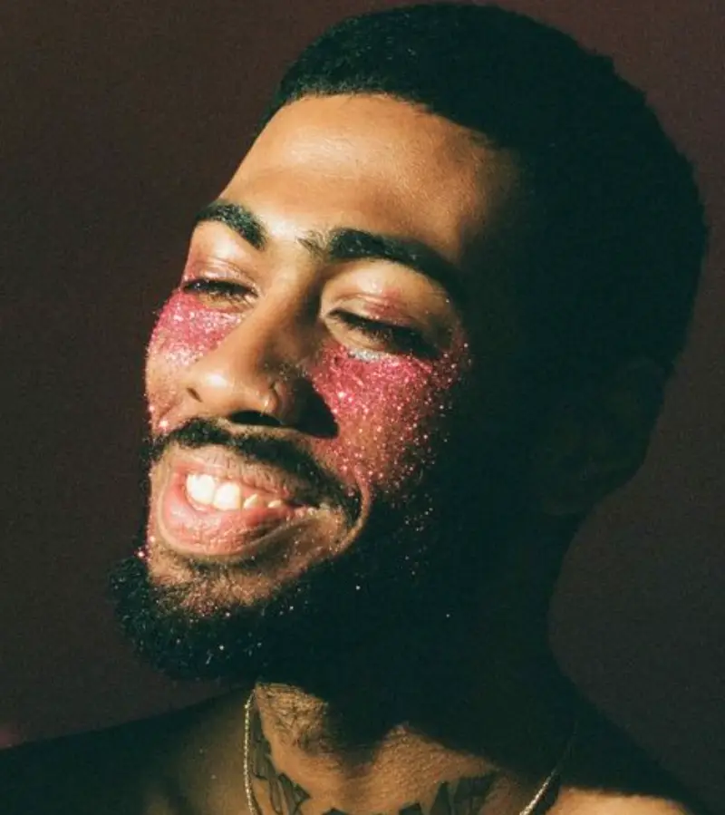 Homem de pele negra com glitter rosa na bochecha