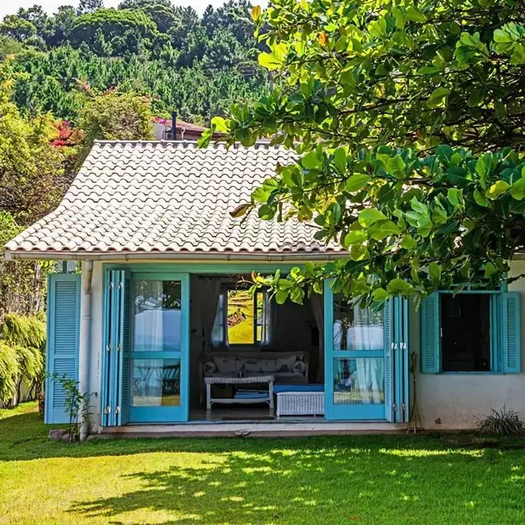Frente de lar em área rural com janelas e protas azuis