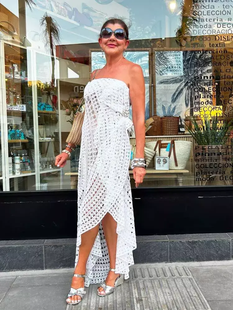 Senhora de pele clara usando vestido branco de crochê com detalhes assimétricos, amarrações e sem alça 