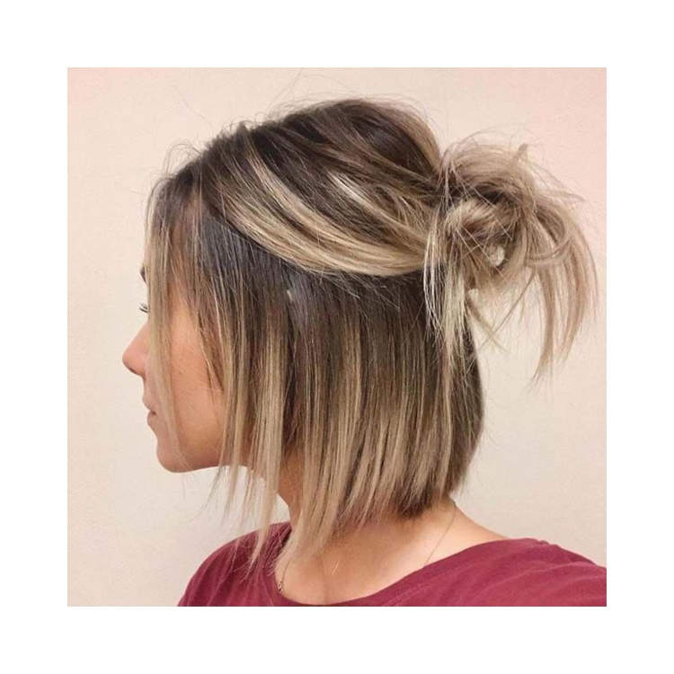 mulher com cabelo loiro curto semi preso com um pequeno coque no topo