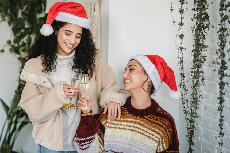 Duas meninas brindando com touca de natal.