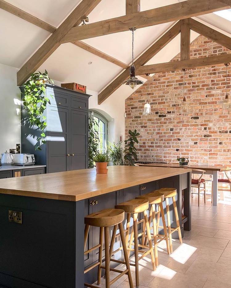 Ilha luxuosa com banquetas de madeira em cozinha com decoração estilo rural