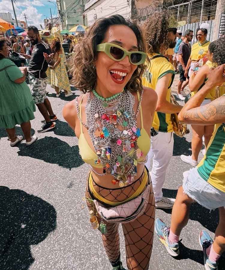 Foto de mulher com look de Carnaval fácil: top, hot pants, meia arrastão e colar de correntes