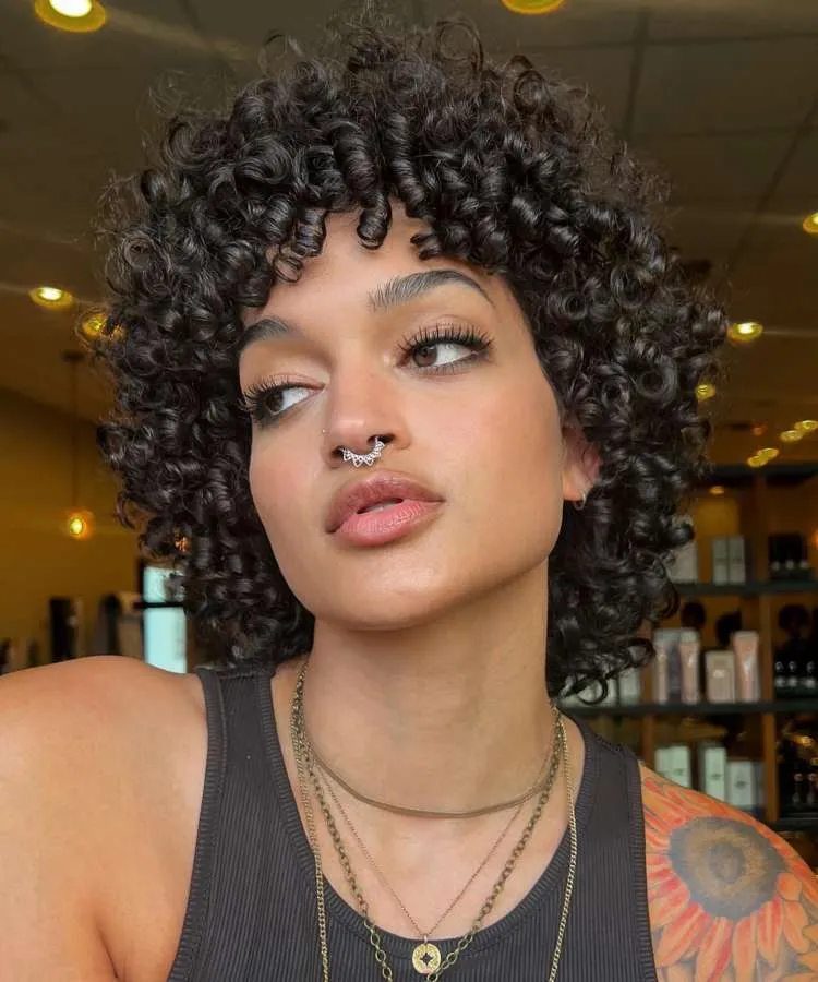 Mulher com cabelo cacheado castanho curto e repicado