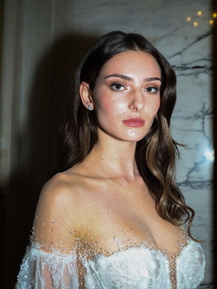 Mulher de pele clara usando vestido de noiva e maquiagem natural, com tons terrosos nos olhos 
