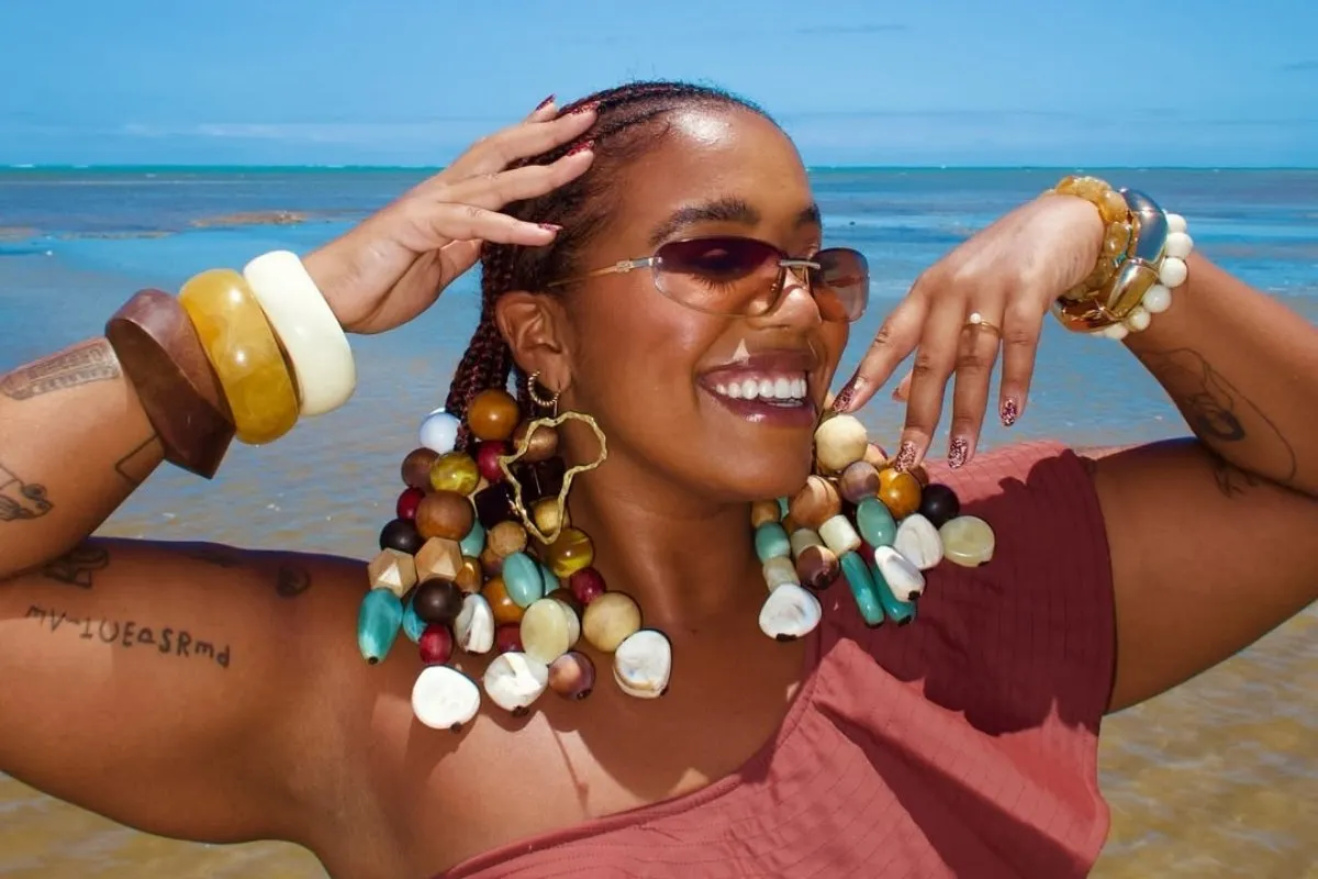 Foto de Mari Lobo, uma das influenciadoras negras de moda, usando biquíni marrom e miçangas no cabelo