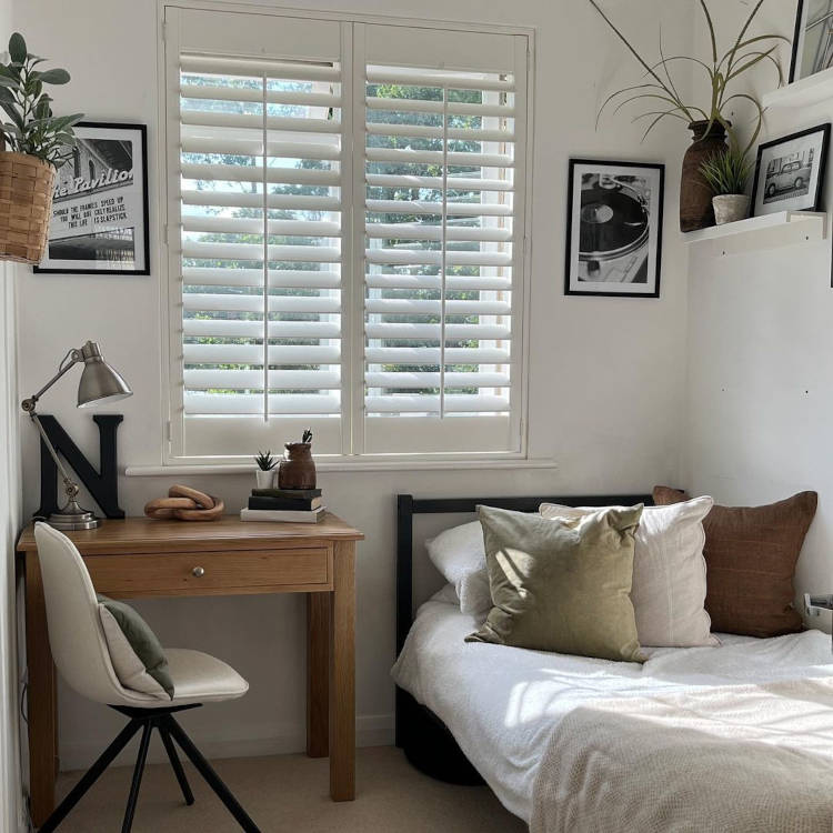 Quarto pequeno decorado com quadros e plantas.