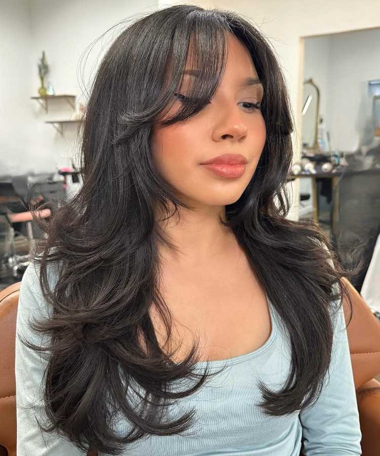 A imagem mostra um corte de cabelo conhecido como "corte em camadas repicado" com franja cortina. Esse estilo é caracterizado por camadas desfiadas que adicionam movimento e volume aos fios, enquanto a franja cortina oferece um toque moderno e suave ao visual.


