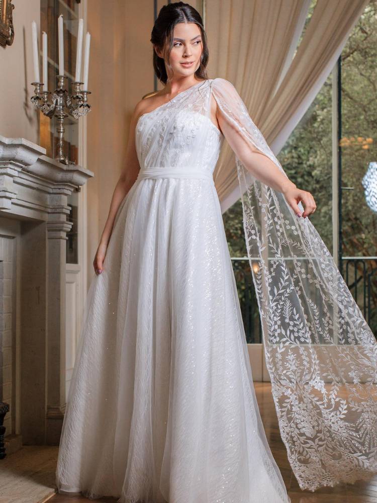 Mulher de pele clara usando vestido de noiva de um ombro só e capa em um ombro