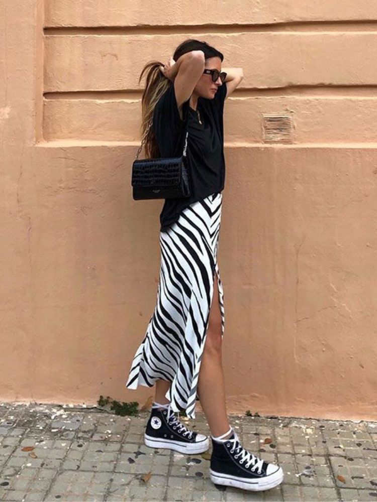 look para lollapalooza com saia animal print de zebra, camiseta preta e all star.