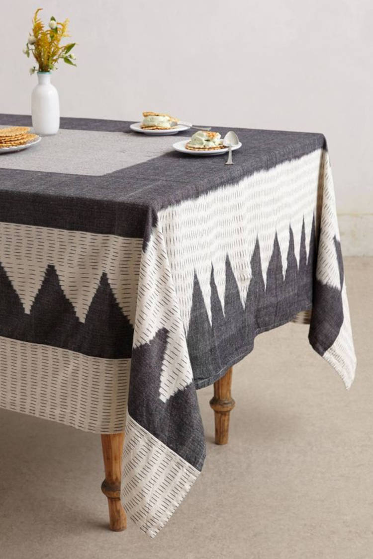 Mesa de jantar com toalha de desenhos cinzas.