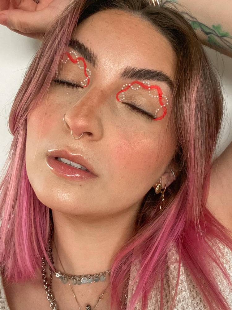 Mulher de pele clara com delineado laranja e com pérolas 