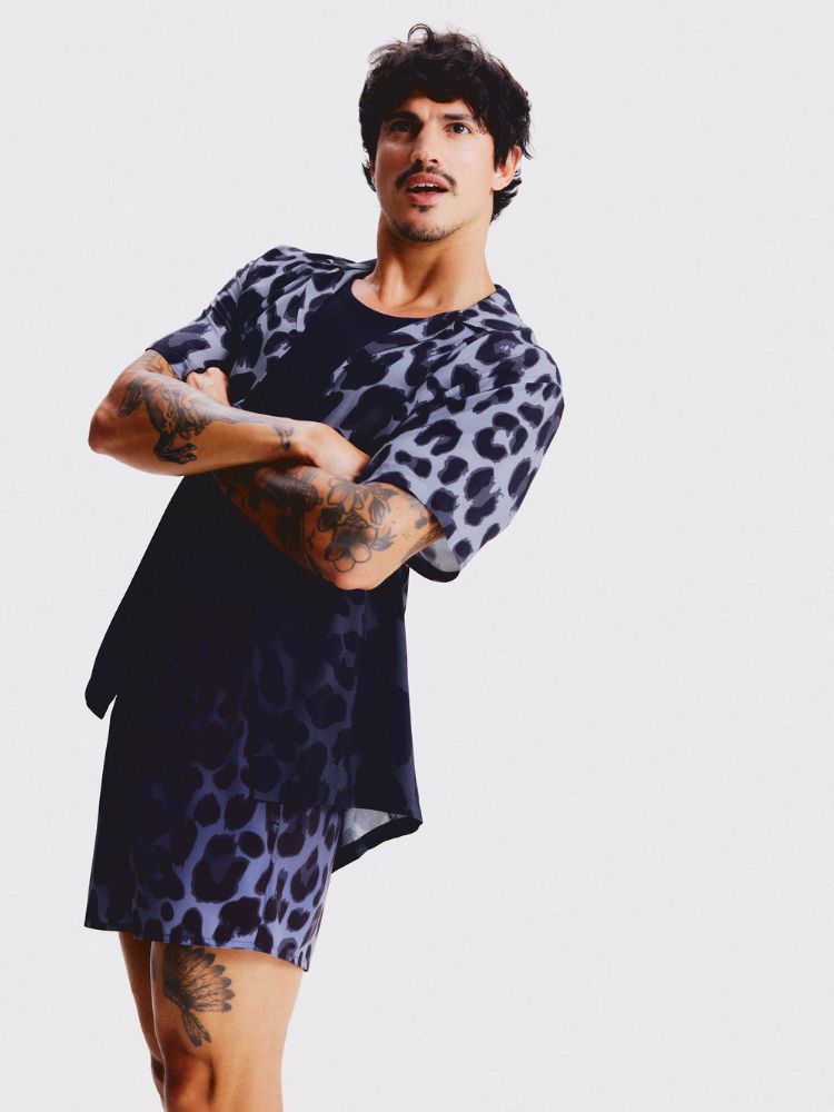 Homem de pele clara usando camiseta e bermuda animal print lilás 