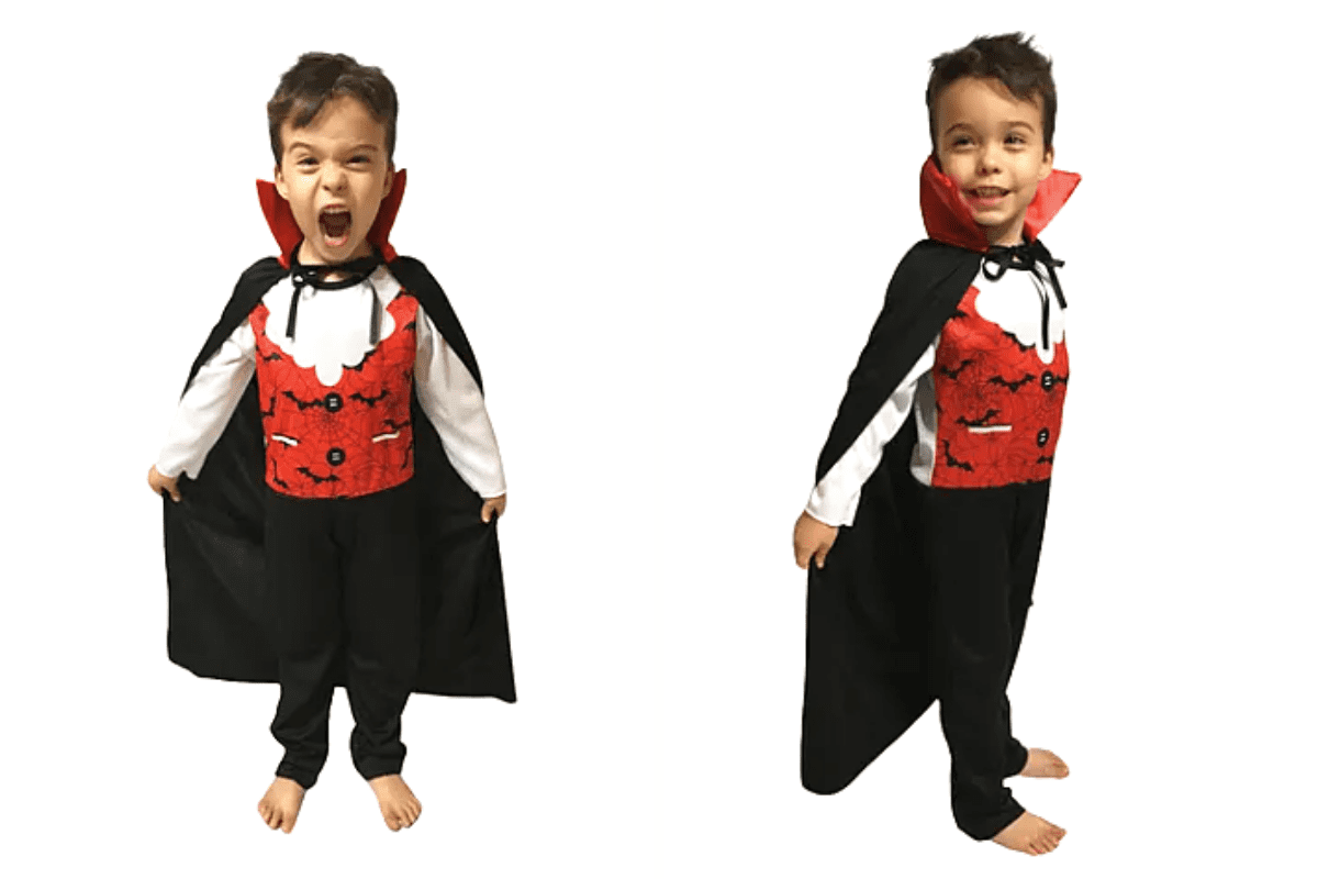 menino fantasiado de vampiro. A fantasia consiste em uma capa preta, colete vermelho e calça preta