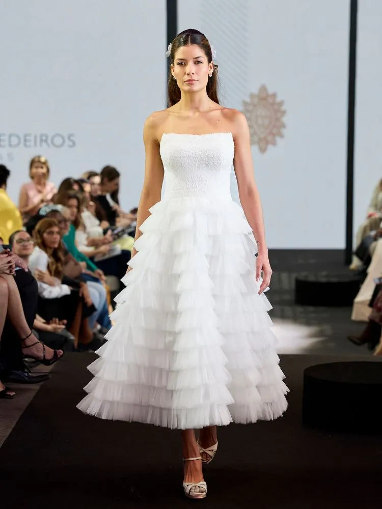 Mulher de pele clara com vestido de noiva midi corseletado e saia de babado de tule