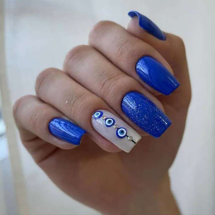 unha quadrada azul grande com glitter e desenhos de olhos-grego