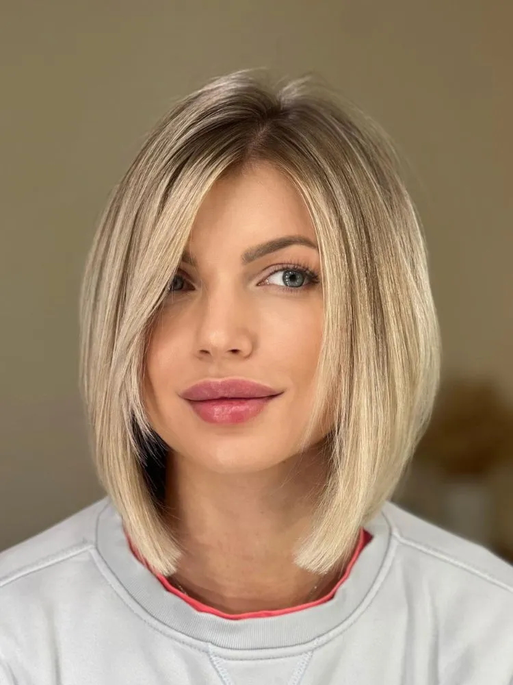 Mulher de pele clara e rosto redondo usando camiseta branca e cabelo cortado em chanel de bico