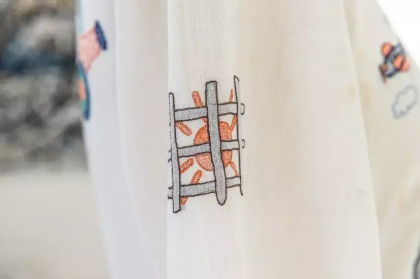 Bordado de um sol enjaulado em um dos vestidos de Zuzu Angel. 