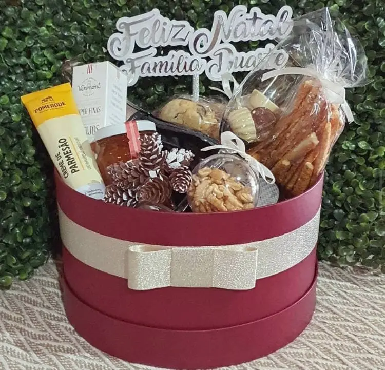 cesta de feliz natal vermelha, com enfeites, creme de quijo, doces e mais 