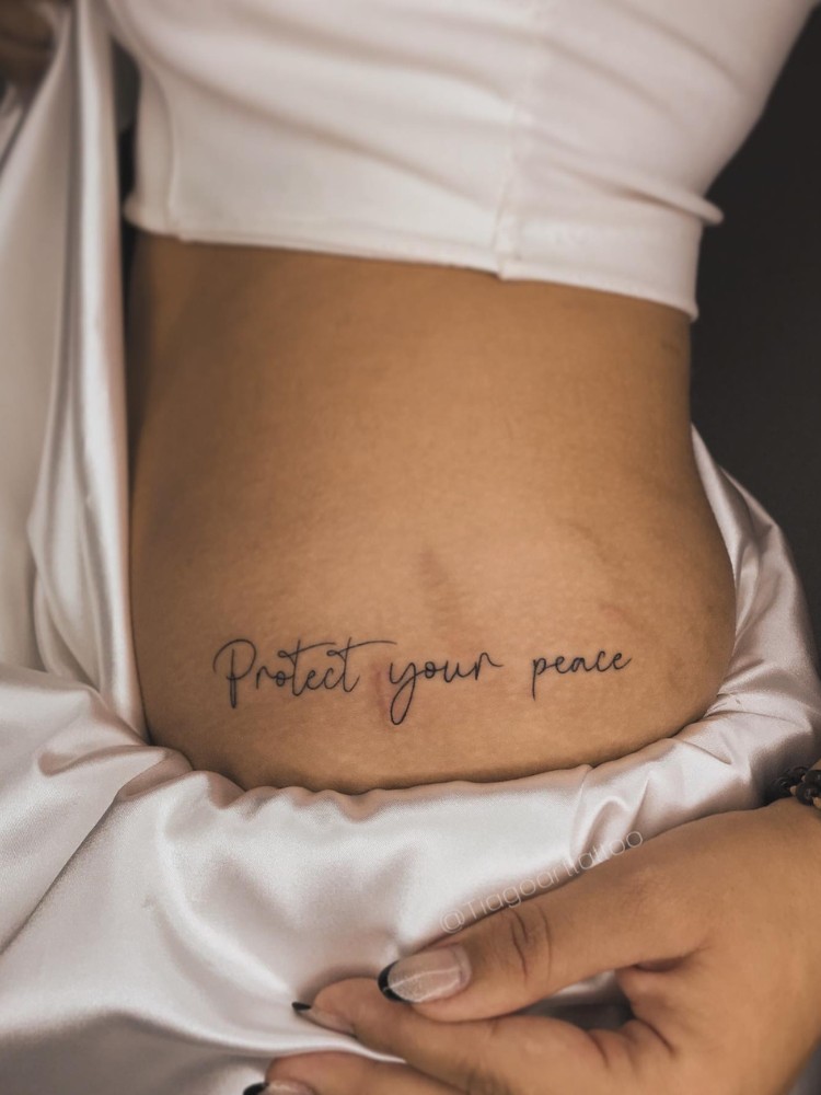 Mulher de pele clara com tatuagem "protect your peace" em fine line
