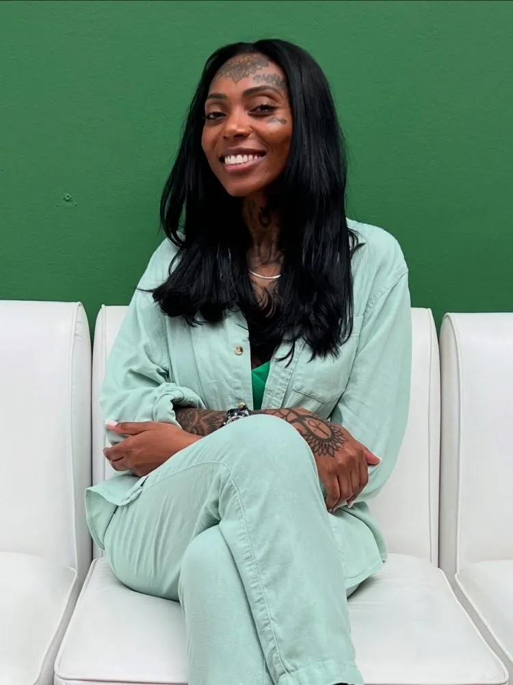 Sára Zarâ de conjunto verde clara, sentada em poltronas claras