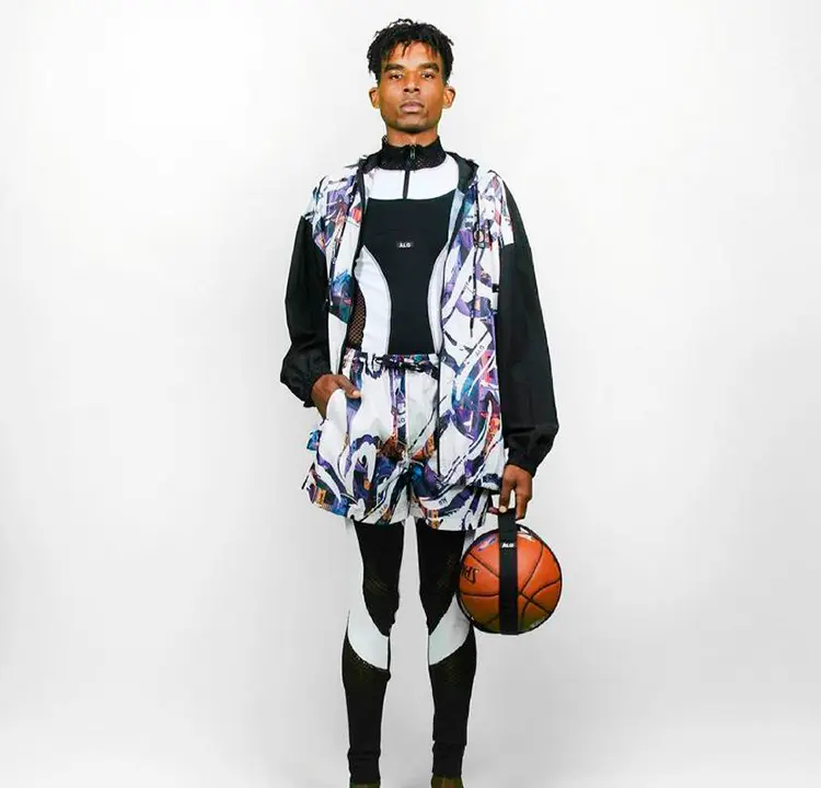 Modelo com roupa atlética preta e short e colete coloridos por cima.