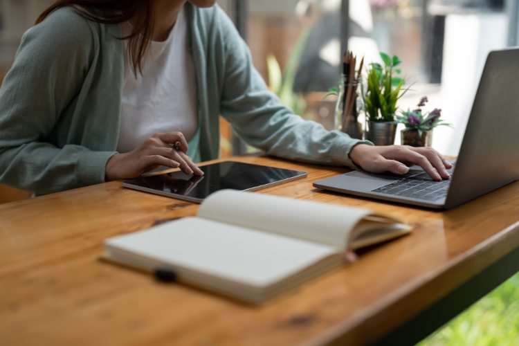 Mulher fazendo curso online em uma mesa de madeira