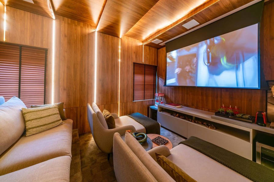Sala que parece cinema com poltronas e telão.