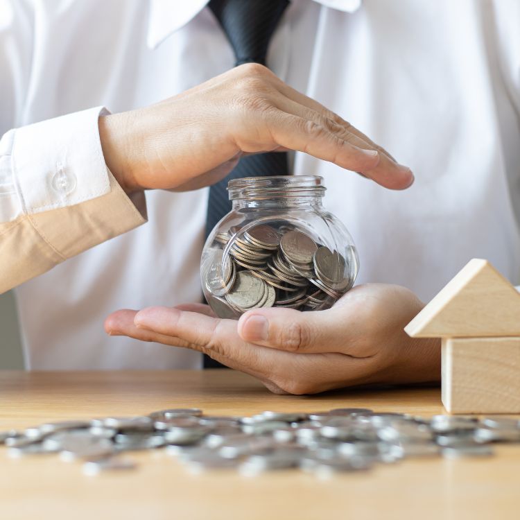 A imagem apresenta uma pessoa protegendo um pote cheio de moedas com as mãos, simbolizando segurança financeira. Em destaque, o conceito de investimentos blindados é reforçado, transmitindo a ideia de proteção e preservação de recursos em cenários desafiadores.