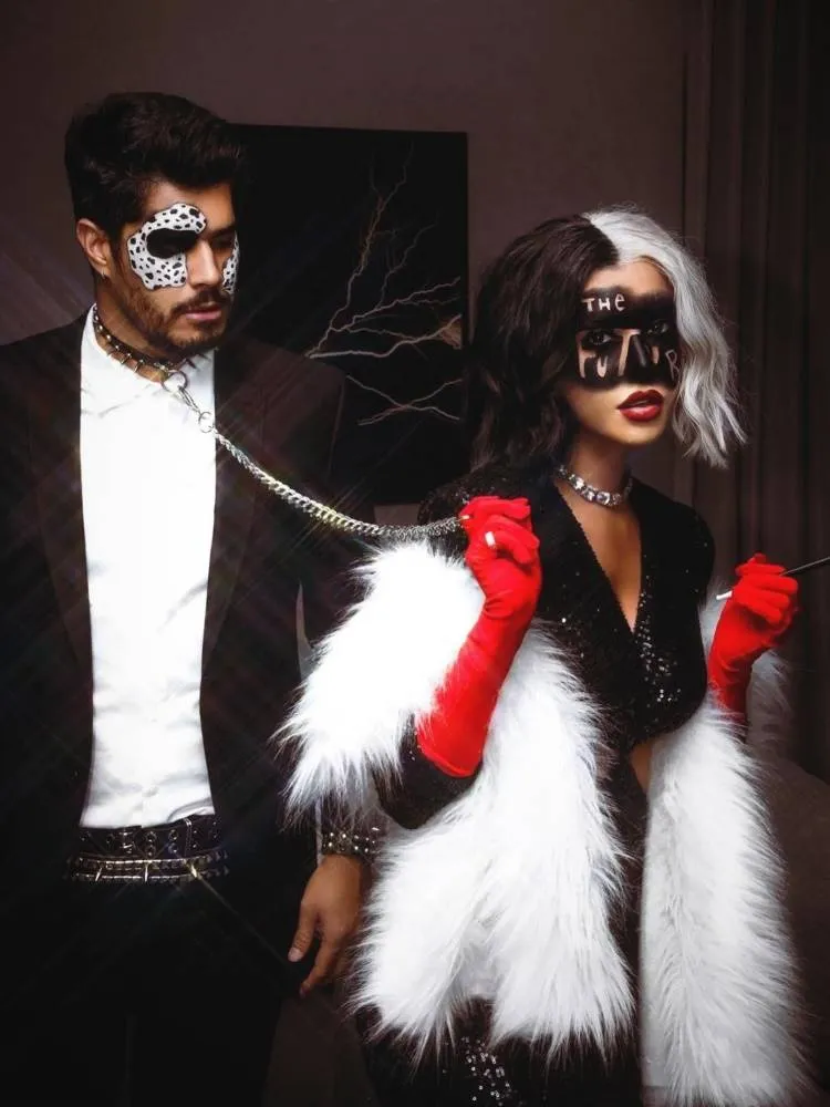 Casal de influenciadores Rica de Marré e Adrão Meron fantasiados de Cruella e seu Dálmata para o Halloween. Ele usa maquiagem de dálmata, coleira, camisa branca e terno, enquanto ela usa cabelo branco e preto, luvas vermelhas e vestido preto 