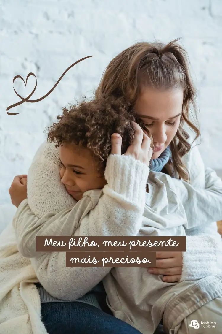 Mãe de cabelo castanho claro e filho, de pele morena e cabelo cacheado, se abraçam. O menino sorri com os olhos fechados, a mãe o abraça carinhosamente, demonstrando afeto e união. A imagem tem a frase "Meu filho, meu presente mais precioso".