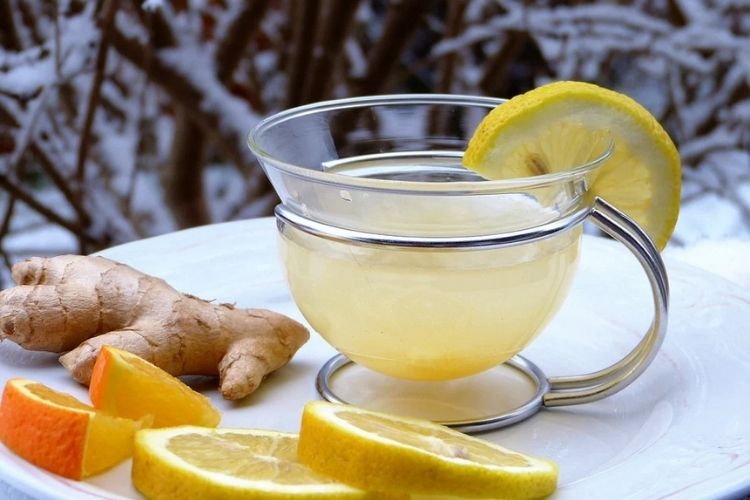 Foto do chá de laranja com gengibre. Tem rodelas de laranja, um copo de chá e gengibre. laranja e gengibre