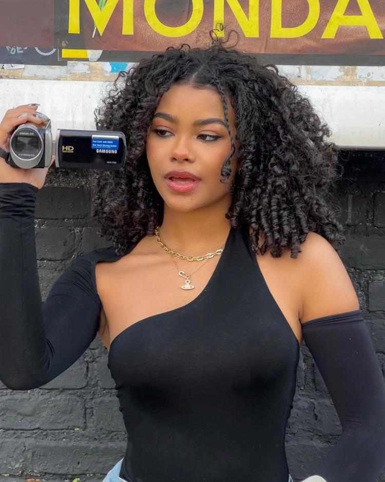 mulher de cabelo cacheado com duas tranças finas frontais e cabelo solto volumoso